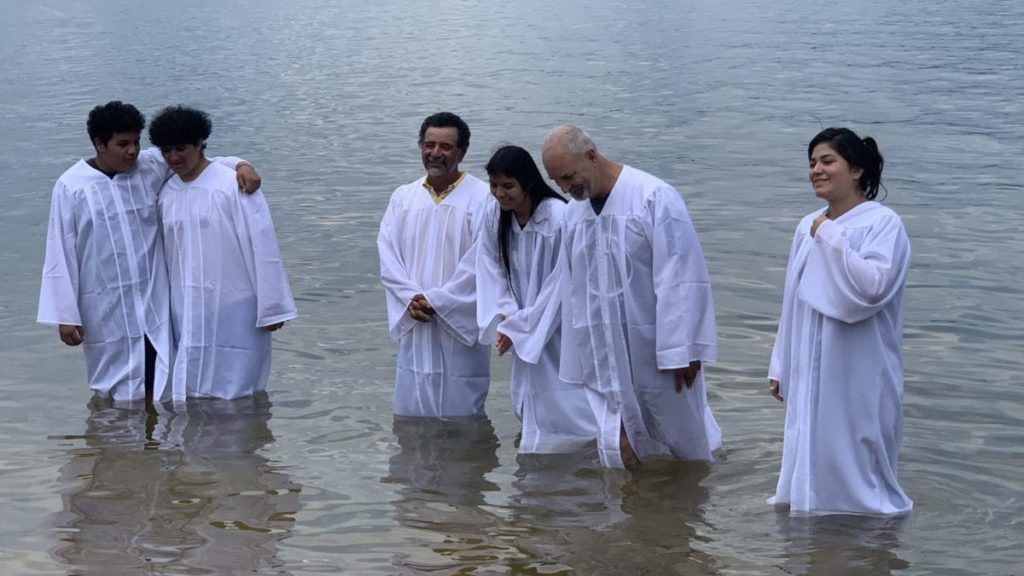 People in white baptism robes standing in lake