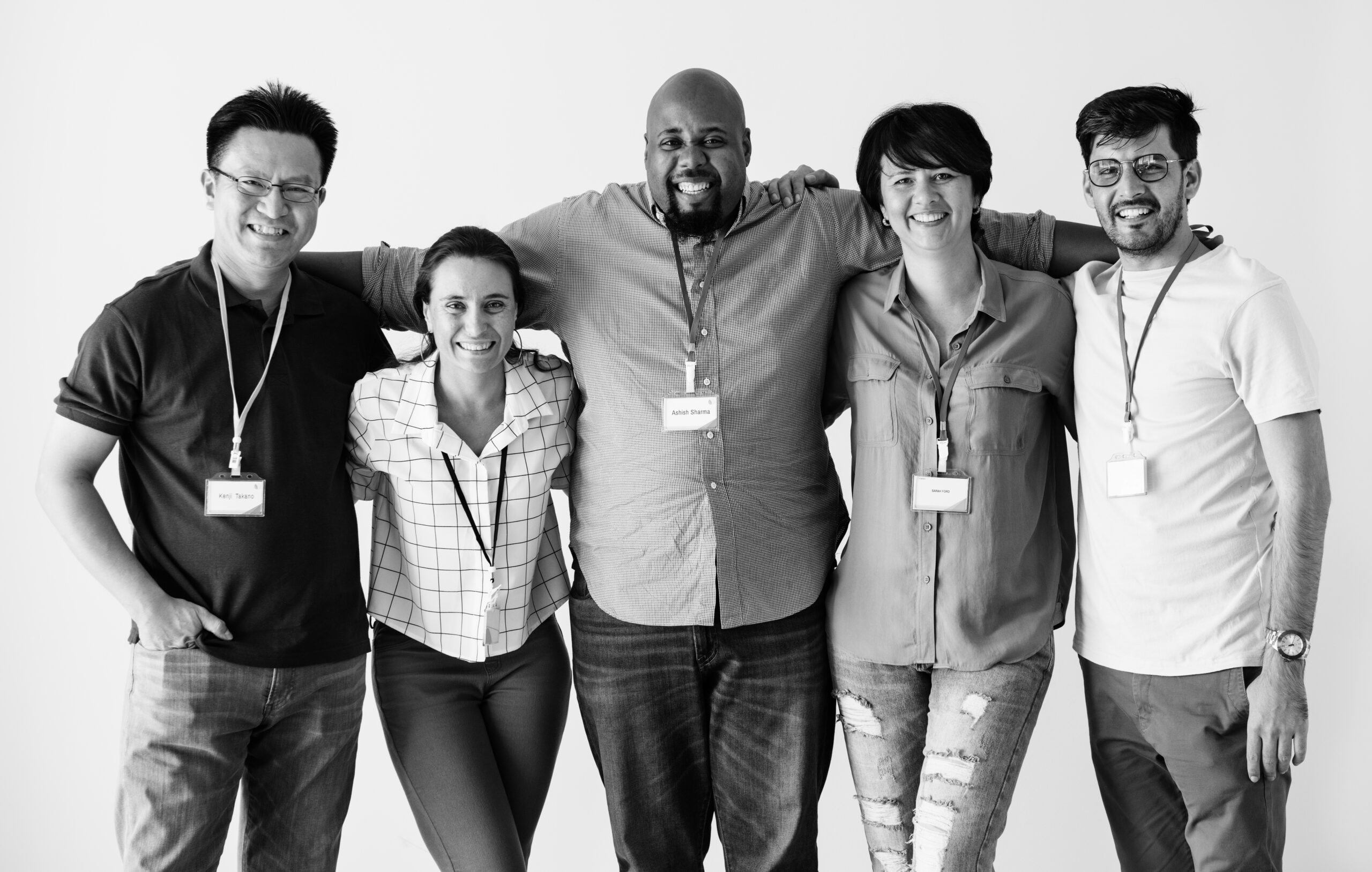 Black and white photo of a diverse group of men and women standing together wearing lanyards