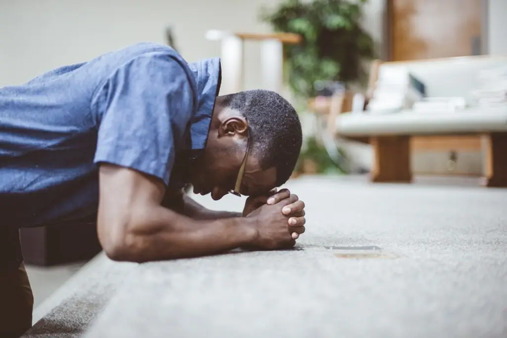 Man praying on his knees with his head down at a church