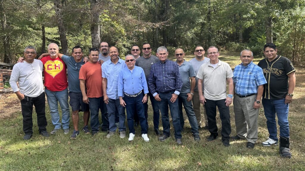 Group of Hispanic church planters standing together outside in front of trees posing for a picture