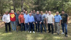 Group of Hispanic church planters standing together outside in front of trees posing for a picture