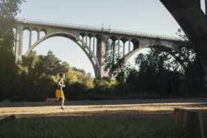 Jogger running a marathon with an arch bridge in background