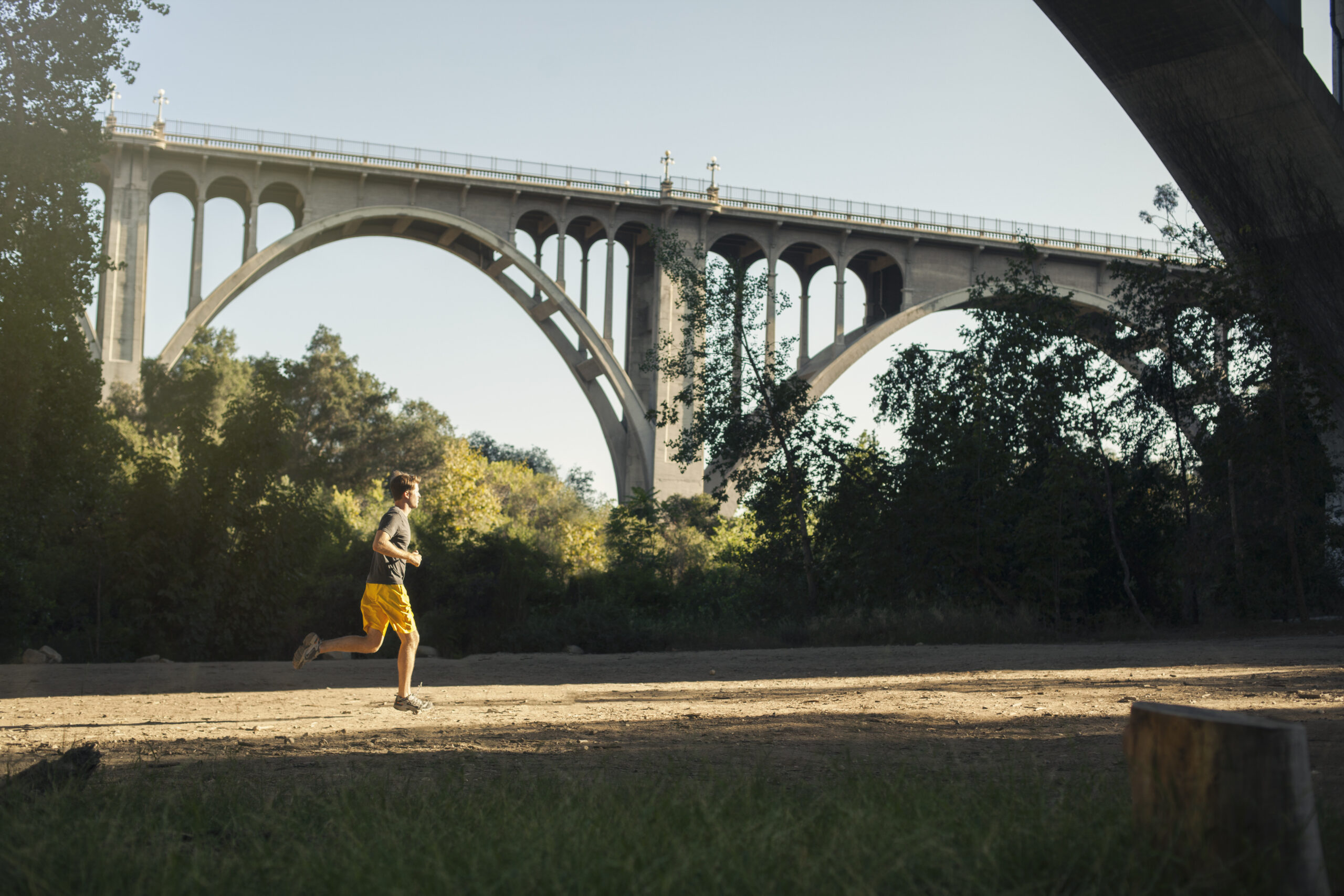 Jogger running a marathon with an arch bridge in background