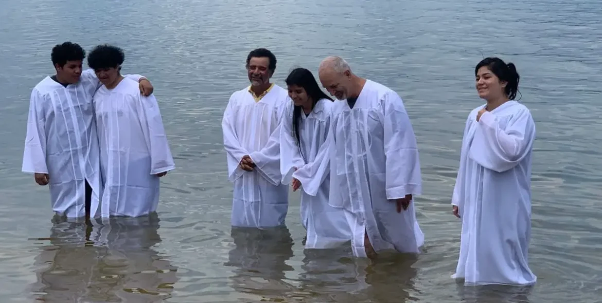 People in white baptism robes standing in lake