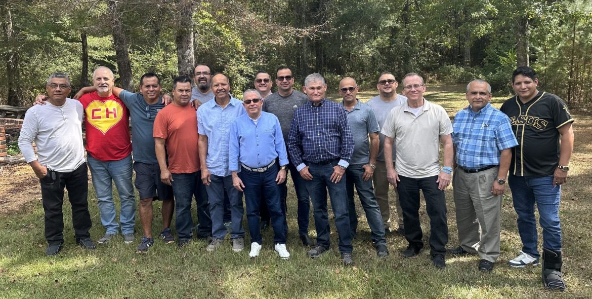Group of Hispanic church planters standing together outside in front of trees posing for a picture