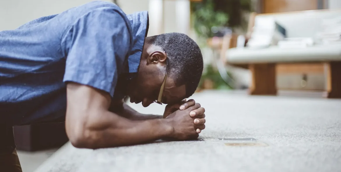 Man praying on his knees with his head down at a church