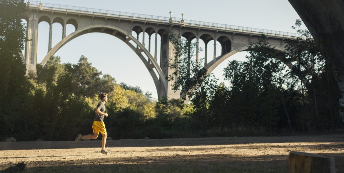 Jogger running a marathon with an arch bridge in background