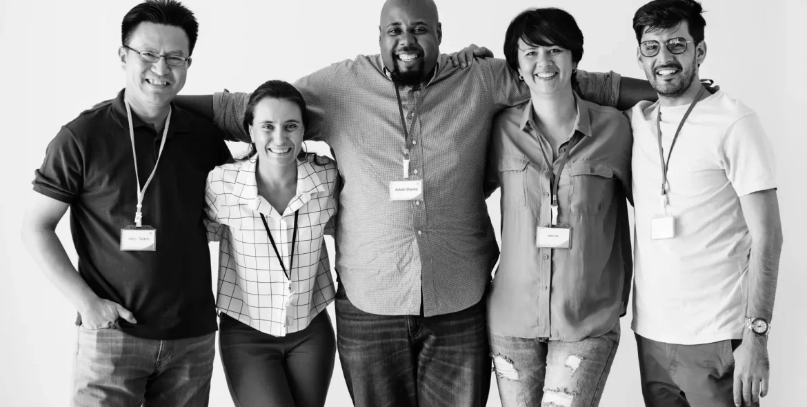 Black and white photo of a diverse group of men and women standing together wearing lanyards